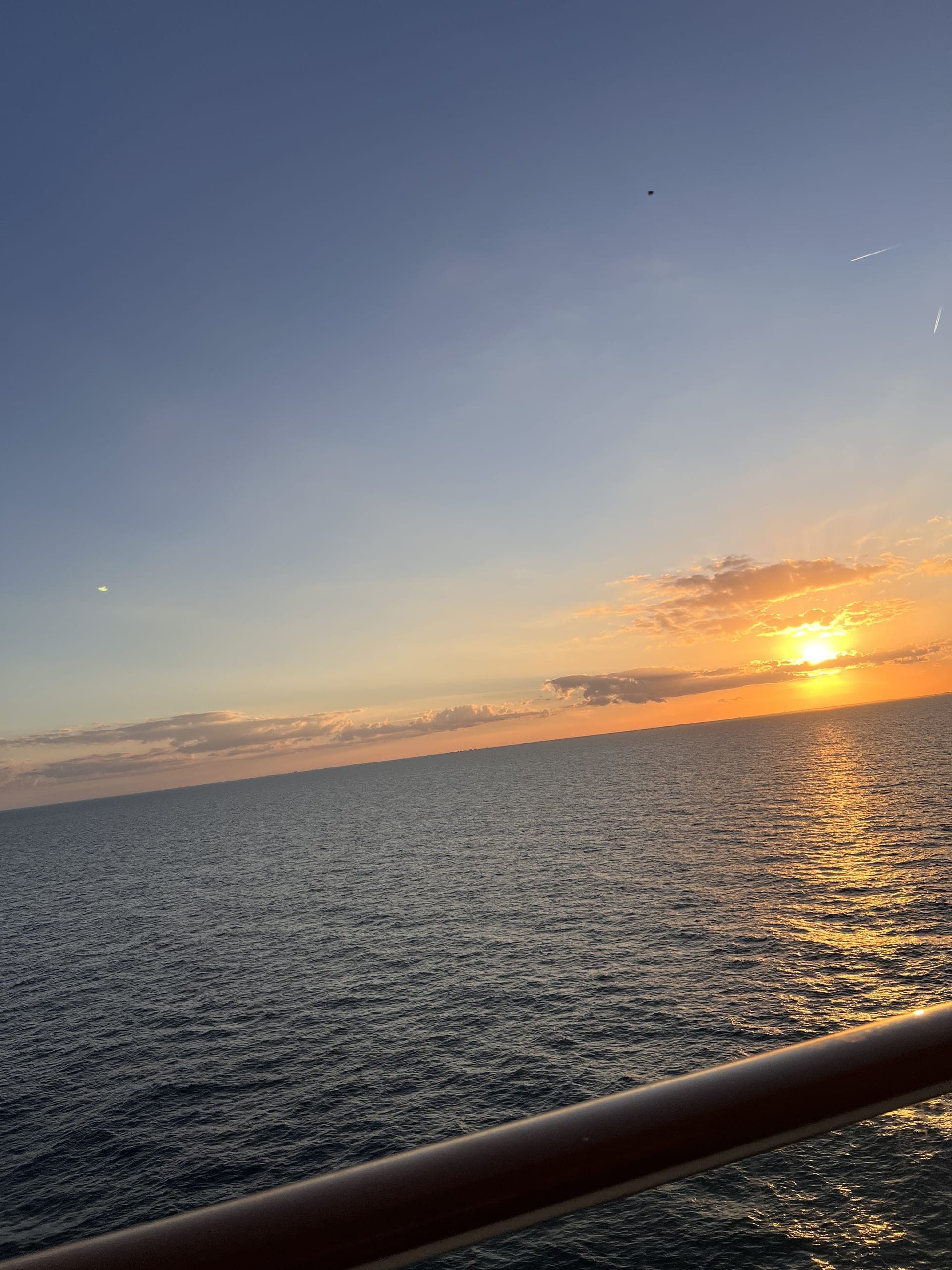 Sunset over the ocean from a cruise ship deck railing